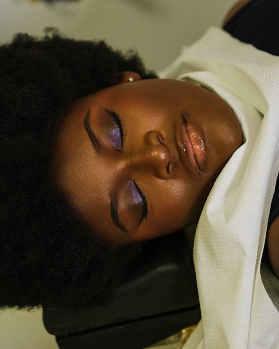 Head spa : yeux fermés, cheveux crépus déployés, la nuque posée sur une serviette